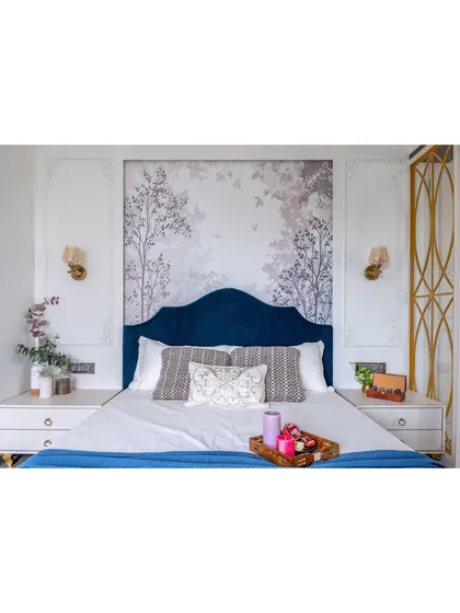 A master bedroom designed as a serene retreat. We balanced a rich blue velvet headboard and a delicate nature-inspired wallpaper with classic wall mouldings and warm lighting to create a space that feels both luxurious and deeply personal.