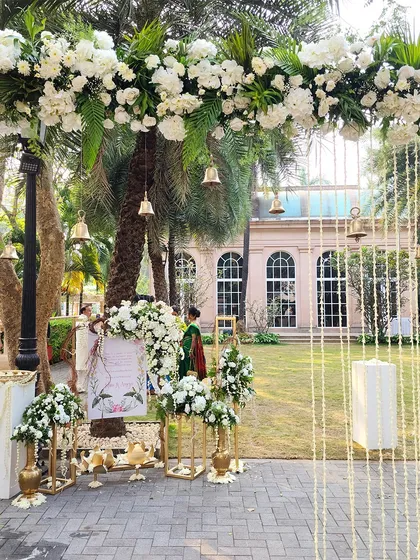 A wider view of the outdoor welcome area, with a floral arch adorned with traditional bells, creating a serene and beautiful entrance.