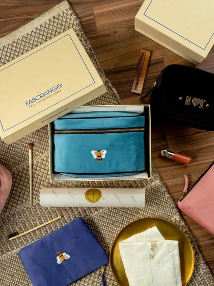 A luxurious flat lay of Faborange's velvet travel pouches. The items are styled as if being unboxed, surrounded by makeup brushes and other accessories to showcase their use as premium cosmetic or travel bags.