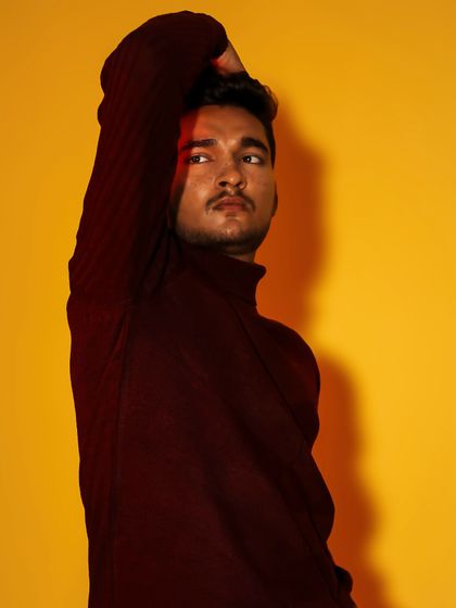 A male portrait where a sliver of red light adds a touch of drama. The pose is thoughtful, set against a vibrant yellow that makes the image pop.