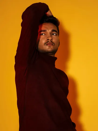 A male portrait where a sliver of red light adds a touch of drama. The pose is thoughtful, set against a vibrant yellow that makes the image pop.