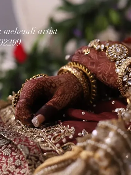 A close-up of the bride's hand, showing the intricate details of the henna stain and her beautiful jewelry.