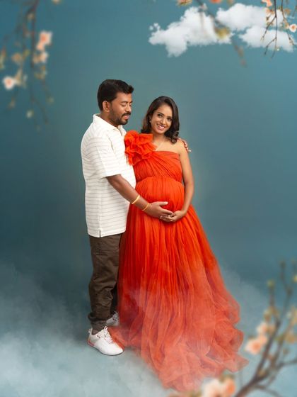 A full-length view of the couple, showing the beautiful ombre effect of the red gown. The dreamy, cloud-like effects at their feet add a touch of magic to this romantic shot.