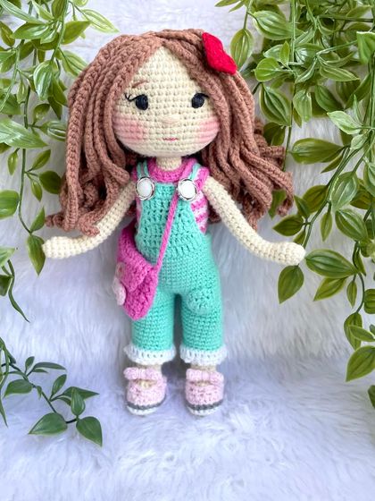 This is the same doll in her second outfit! This set includes mint green overalls, a pink floral bag, and a cute red hair clip. Having multiple outfits makes playtime even more exciting.