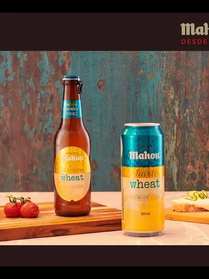 Presenting the Mahou Wheat variant in both bottle and can formats. The rustic blue background and simple food pairings create a visually distinct look for this product line.