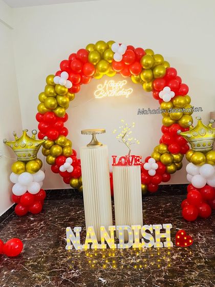 This royal-themed birthday decoration features a circular balloon arch in red and gold. I added fun details like balloon columns topped with gold crowns and marquee letters spelling out the name.