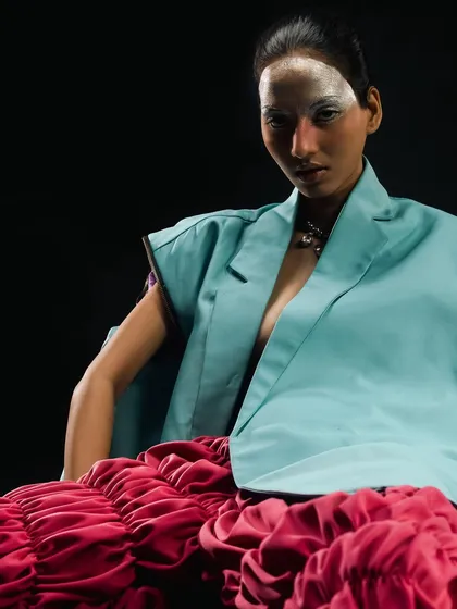 A seated portrait from the "Metaverse" series, showing the silver face makeup and sleek hair against the structured fashion.