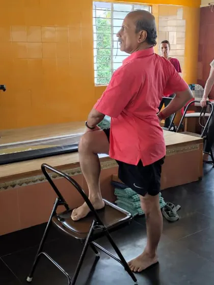 A preparatory standing pose using a chair.