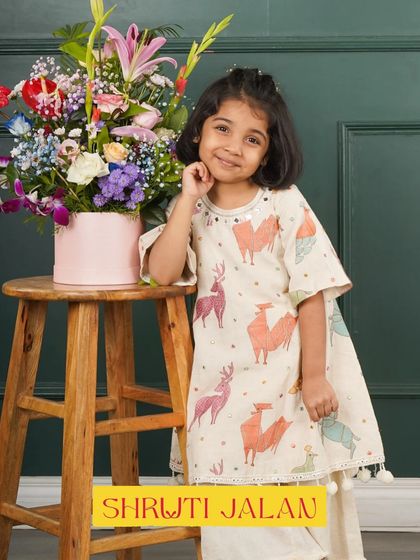 This little girl looks so sweet in my llama-print kurta set. The asymmetrical top and pom-pom details add a modern and playful touch to this adorable outfit.