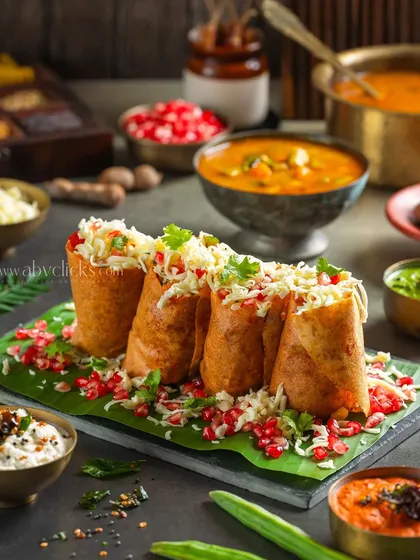 Jini Dosa, a popular street-style dish, presented as small, cheese-filled rolls. The styling is vibrant and appetizing.
