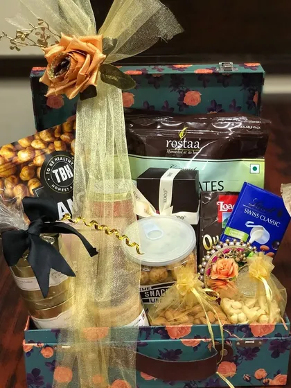 A luxurious welcome hamper packed in a floral-printed trunk box. This gift is filled with premium snacks, dry fruits, and chocolates, perfect for making guests feel pampered.