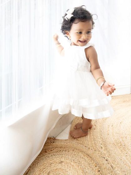 A sweet, candid shot of the baby girl exploring by the window, with the light creating a beautiful glow.