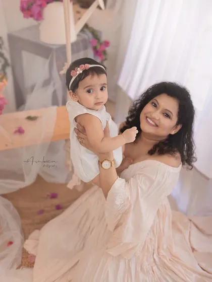 A bright, happy portrait of mother and daughter. Her smile is radiant as she holds her baby, creating a memory filled with warmth and love.