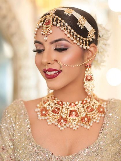 A beautiful bride looking radiant in a custom red and orange meenakari choker set. The matching mathapatti and nath complete her elegant and traditional look.