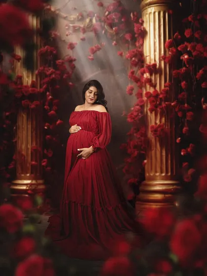 In my studio, we can create bold and moody portraits. Here, a beautiful mom to be is surrounded by red roses and dramatic lighting, creating a powerful and romantic image of motherhood.