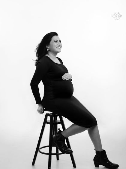 A stylish black and white portrait of a mom-to-be in a sleek black dress and boots, exuding confidence and modern motherhood.