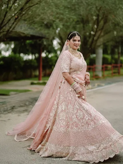 The bride, radiant in her pink lehenga, gives a joyful twirl. A perfect bridal portrait full of life and happiness.