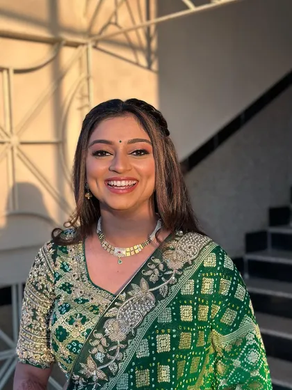 A happy client showing off her beautiful green lehenga and unique hairstyle.