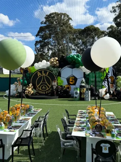 The dining area of the football party, with themed table settings and large balloons, perfectly complementing the main stage.