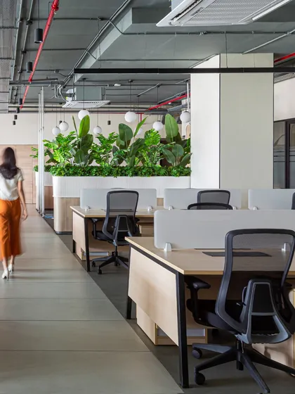 Greenery is a key element in this workspace, used here as a natural divider that adds life and color. These large planter boxes help define zones without closing off the space, maintaining the office's open and breathable feel.