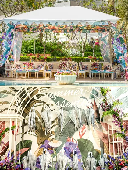 A tropical-themed setup with vibrant floral prints on the canopy and cushions. The backdrop features a playful umbrella installation, adding a touch of summer fun to this outdoor event.