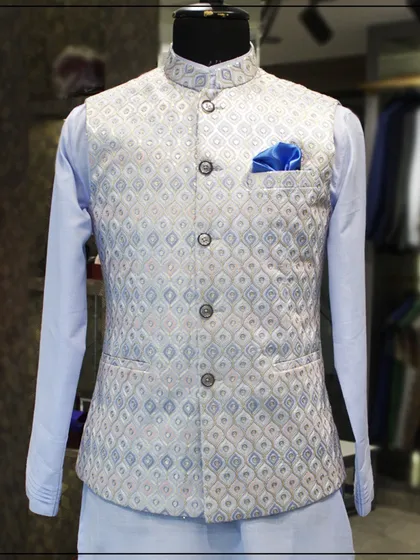 A stylish kurta set with a light blue shirt and a silver-blue patterned Nehru jacket. The blue pocket square adds a nice touch of color.