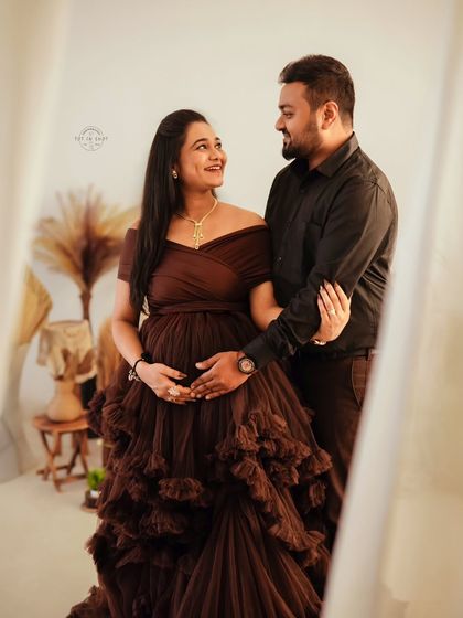 A loving gaze between partners, both dressed in complementary dark tones that make their connection the focus of this maternity portrait.