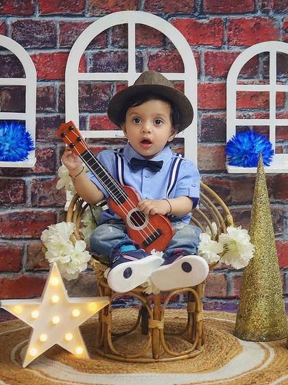 Our very own little Bollywood hero! This fun sitter session captures a filmy vibe with a brick wall backdrop and a tiny guitar.