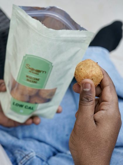 A close-up of a hand holding one of my low-calorie snacks, taken from the bag. It's snacking made simple, with real flavour and clean ingredients.