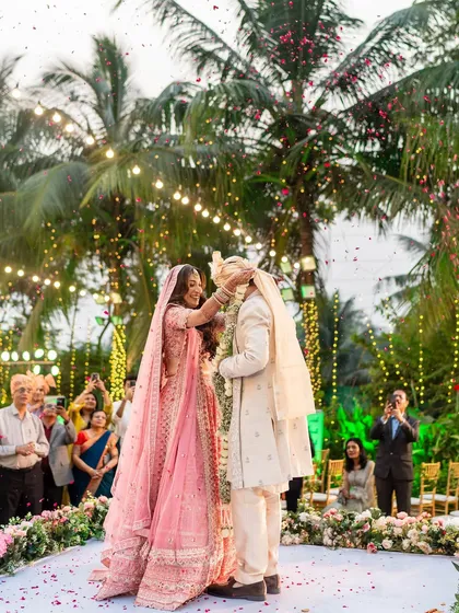 Another angle of the playful varmala, showcasing the beautiful outdoor setting and the joy of the moment.