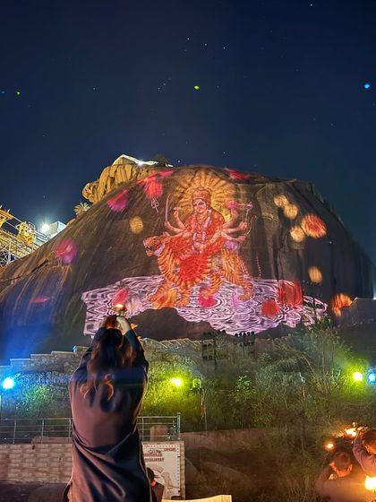 A spectacular light show projecting the image of Goddess Ambaji onto the sacred mountain during the National Women's Archery Tournament.