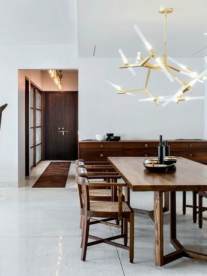 This open-plan dining and living area in the Terrazzo Residence showcases our minimalist approach. The space is defined by a few carefully chosen pieces, like the indoor swing and a modern brass chandelier, which add character without creating clutter.