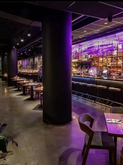 The interior of LokalJC illuminated with purple light, showcasing the dynamic lighting design that transforms the mood of the space from day to night.