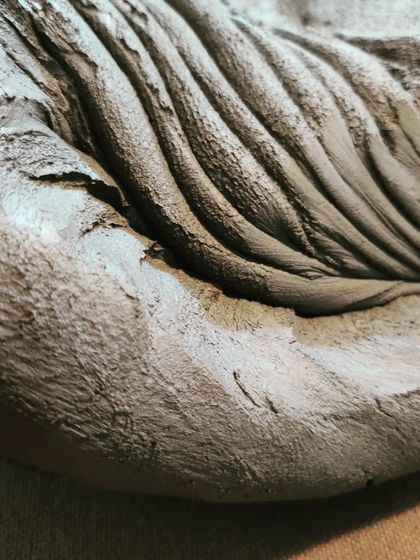 A detailed shot of the folds in a freshly kneaded block of clay. This preparation ensures there are no hidden air pockets that could cause a piece to crack or break during firing.