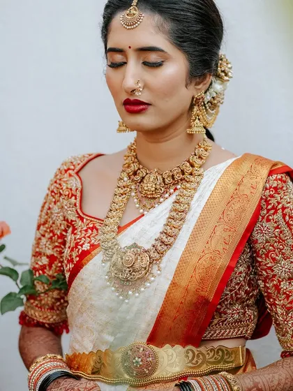 A serene portrait of bride Chaitra. The rich red and gold embroidery on her blouse stands out against the elegant off-white silk of her saree.