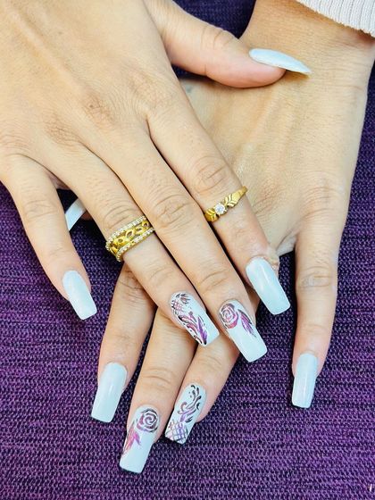 An elegant set of white nails with intricate, hand-painted rose and filigree designs in a deep red.