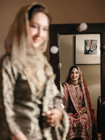 An artistic shot of the bride looking in the mirror while her mother looks on. This creative composition speaks of reflections, generations, and a mother's pride.