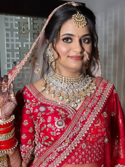The bride adjusts her veil, giving a glimpse of the intricate hairstyle and makeup details that complete her stunning look.
