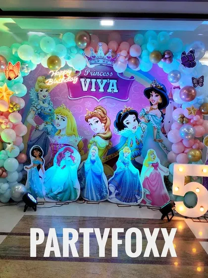 A full view of the Disney Princess themed party for Viya, showcasing the detailed backdrop, balloon arch, and character cutouts.