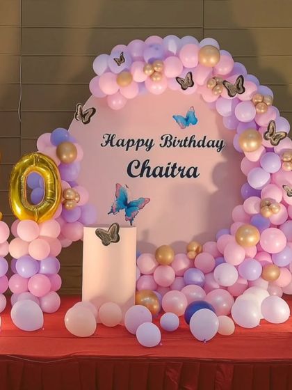 A beautiful butterfly-themed 10th birthday backdrop. The setup uses pastel pink, purple, and gold balloons, with butterfly stickers and large number "10" foil balloons.