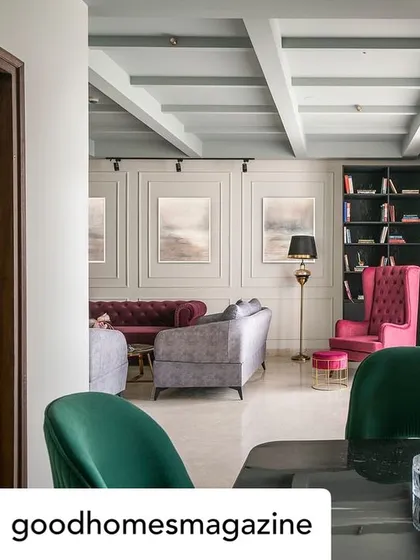 A view from the dining area into the living room, showcasing the harmonious flow between the spaces. The green dining chairs complement the pink and grey tones of the lounge furniture, creating a cohesive color story.