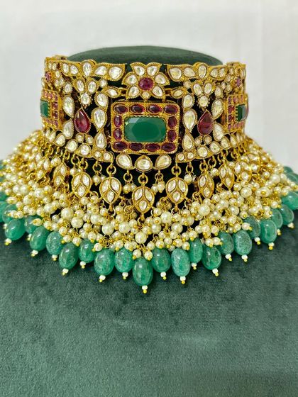 A detailed view of a bridal choker with green beads and pearl detailing. This rental piece is perfect for a traditional bride.