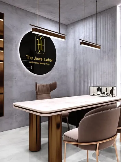 The consultation area in the jewelry studio, with a large table and elegant seating. The brand's logo is prominently displayed, and the lighting is carefully arranged to accentuate the brilliance of the jewelry.