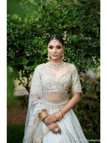 A beautiful medium shot of the bride, focusing on her intricate jewelry and makeup. Her confident and direct gaze makes for a powerful and captivating bridal portrait.