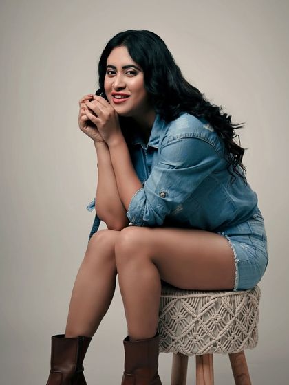 A relaxed and confident studio portrait. The denim-on-denim look and the model's easy smile create a friendly and approachable vibe.