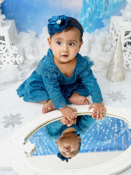A winter wonderland princess. Her reflection in the mirror adds a magical touch to this frosty, snowflake-themed photoshoot.