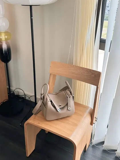 The Linde Large bag styled in a modern home setting, resting on a wooden chair. This shows how the bag is not just an accessory, but a beautiful object in its own right.