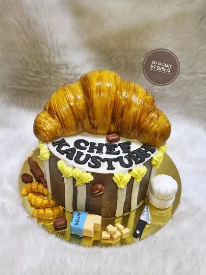 What do you bake for a chef? A cake that looks like their specialty. This piece features a giant, flaky-looking croissant on top, all made from cake and fondant, celebrating the recipient's culinary passion.