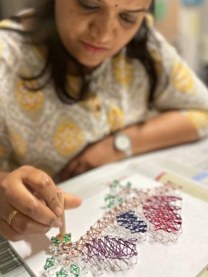 Another angle showing the careful and focused work that goes into creating a detailed string art piece.