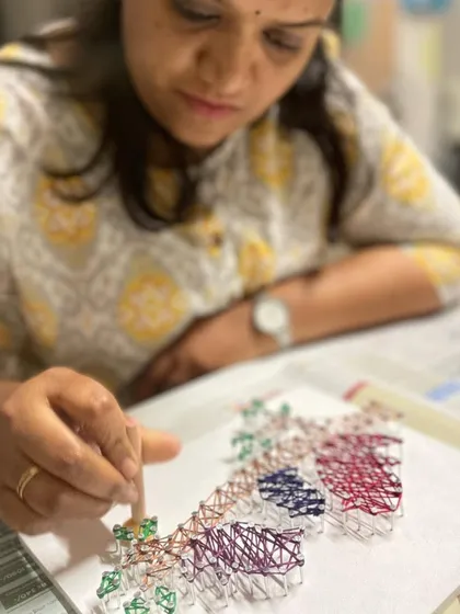 Another angle showing the careful and focused work that goes into creating a detailed string art piece.